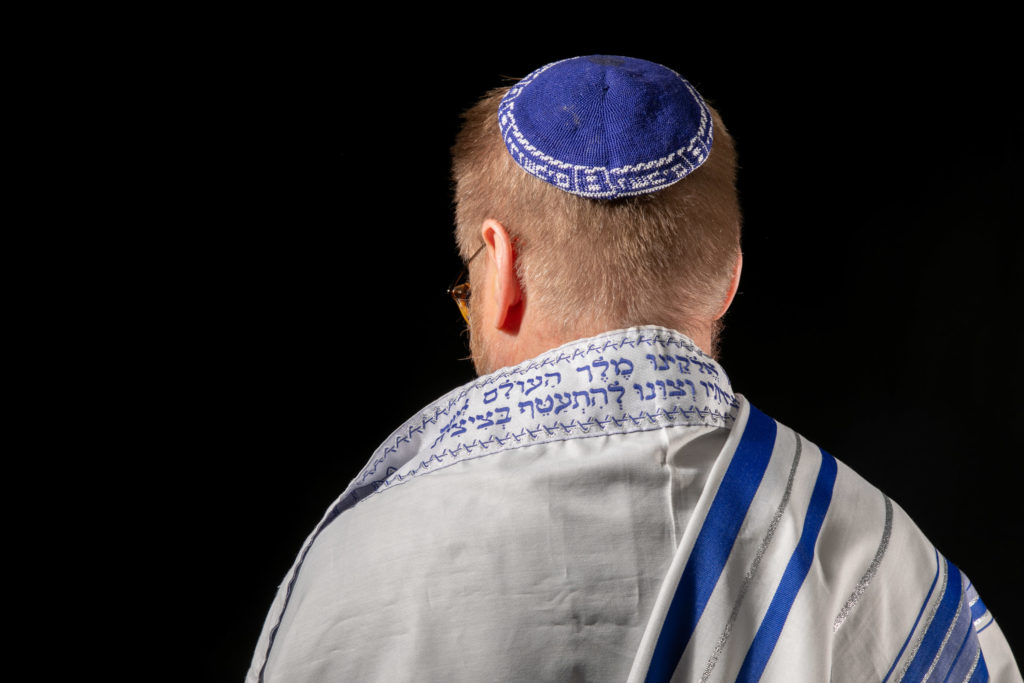 En man med en judisk kipa på huvudet och en bönemantel runt axlarna.